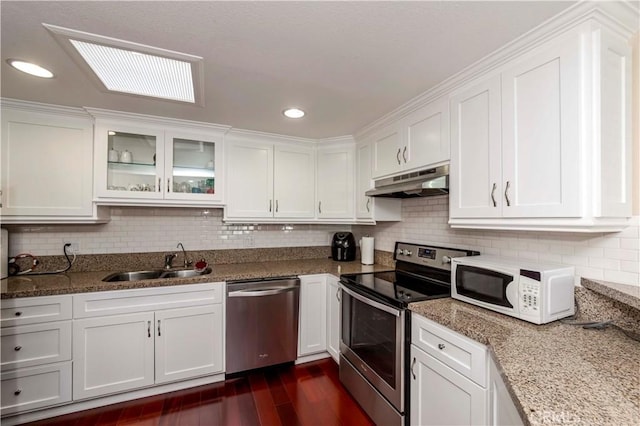 kitchen with light stone countertops, stainless steel appliances, white cabinetry, and sink