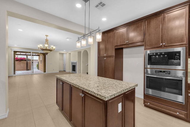 kitchen with decorative light fixtures, a kitchen island, an inviting chandelier, dark brown cabinetry, and built in microwave