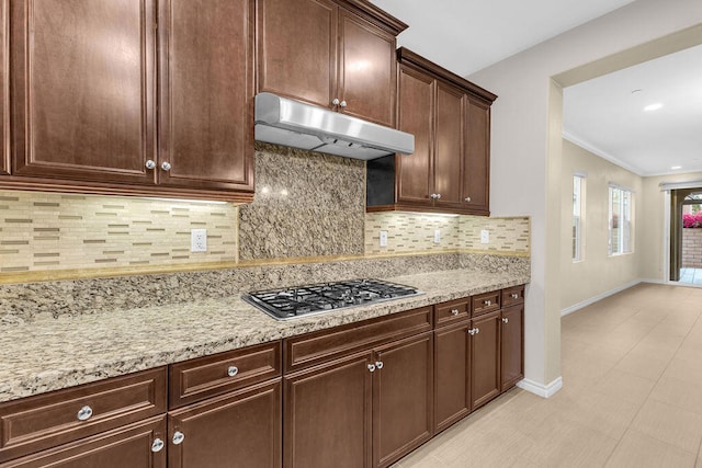 kitchen with tasteful backsplash, stainless steel gas cooktop, and light stone countertops