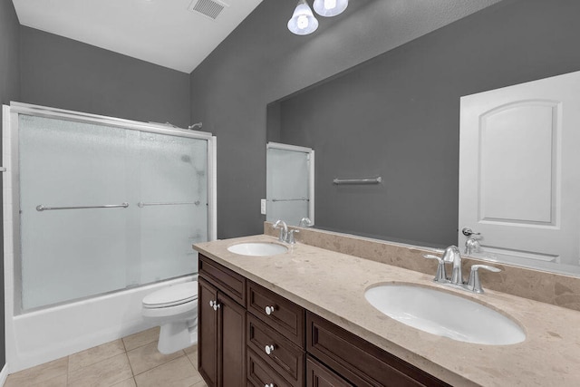 full bathroom with bath / shower combo with glass door, toilet, vanity, and tile patterned flooring