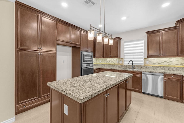 kitchen with light stone countertops, appliances with stainless steel finishes, a center island, sink, and hanging light fixtures