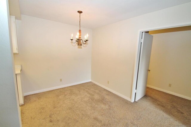 carpeted spare room with an inviting chandelier