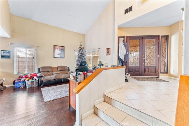 foyer entrance featuring light wood-type flooring, high vaulted ceiling, and french doors