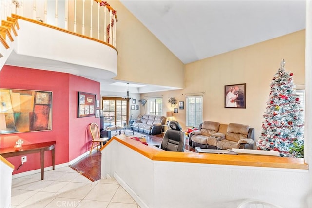 living room with high vaulted ceiling, light tile patterned floors, and a notable chandelier