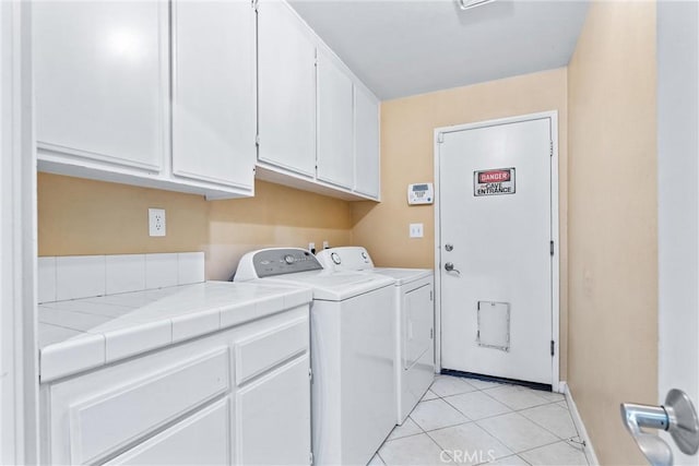 laundry room with washer and clothes dryer, light tile patterned floors, and cabinets