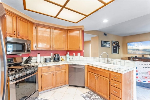 kitchen with kitchen peninsula, tile counters, stainless steel appliances, light tile patterned floors, and sink