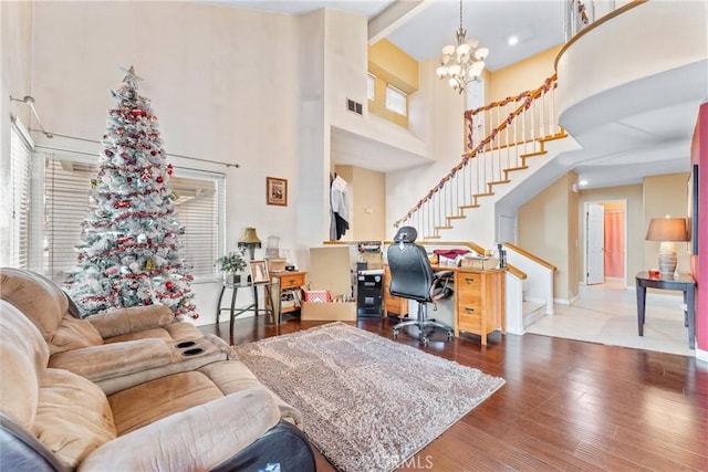 living room with beamed ceiling, a towering ceiling, a chandelier, and wood-type flooring