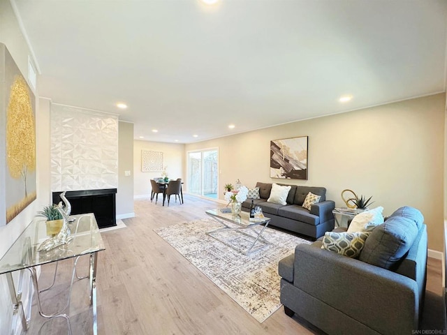 living room with a tiled fireplace and light wood-type flooring