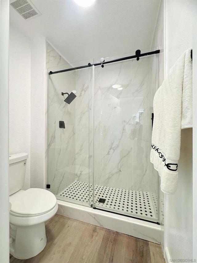 bathroom featuring toilet, hardwood / wood-style floors, and a shower with door