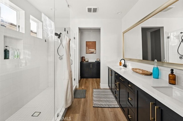 bathroom featuring hardwood / wood-style floors, vanity, and a tile shower