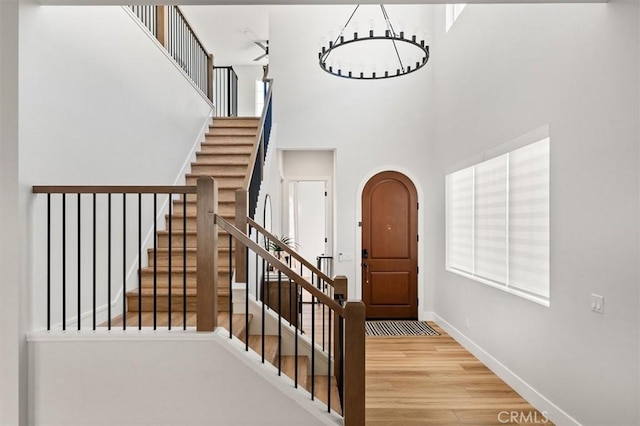 staircase featuring a high ceiling, a chandelier, and hardwood / wood-style floors