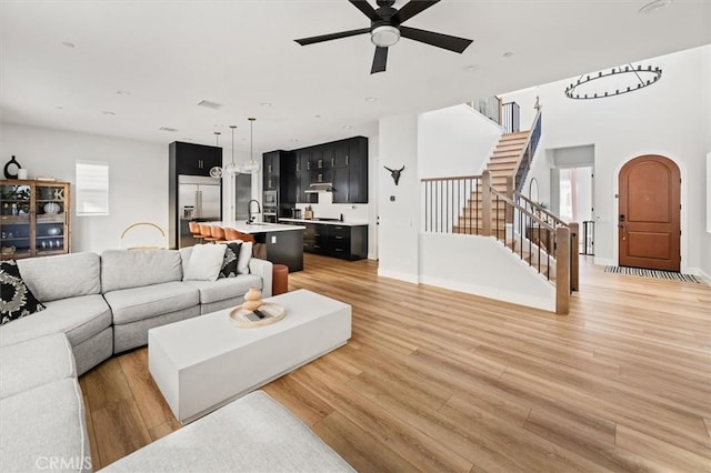 living room featuring ceiling fan, light hardwood / wood-style floors, and sink