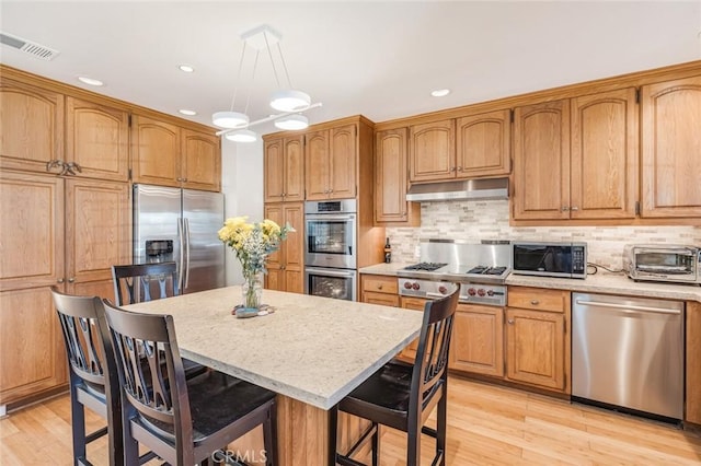 kitchen featuring a center island, hanging light fixtures, a breakfast bar area, light wood-type flooring, and stainless steel appliances