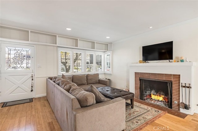 living room featuring light hardwood / wood-style floors, a brick fireplace, and ornamental molding