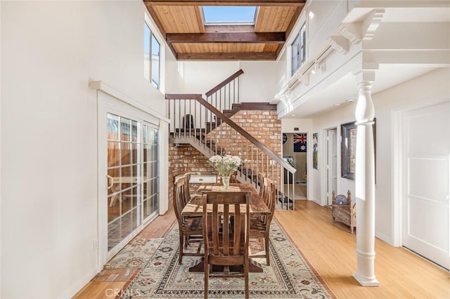 dining room featuring beamed ceiling, light wood-type flooring, high vaulted ceiling, and wood ceiling