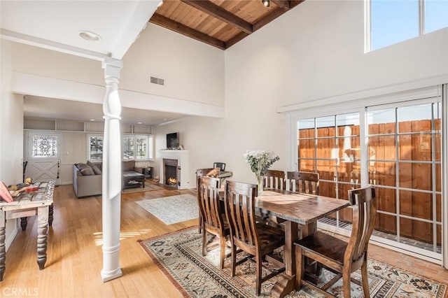 dining space with high vaulted ceiling, ornate columns, beamed ceiling, wood-type flooring, and wood ceiling