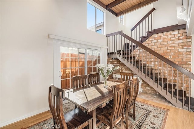 dining space featuring hardwood / wood-style floors, beam ceiling, high vaulted ceiling, and wood ceiling