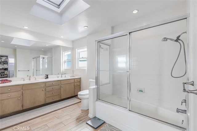 full bathroom featuring vanity, toilet, shower / bath combination with glass door, and a skylight