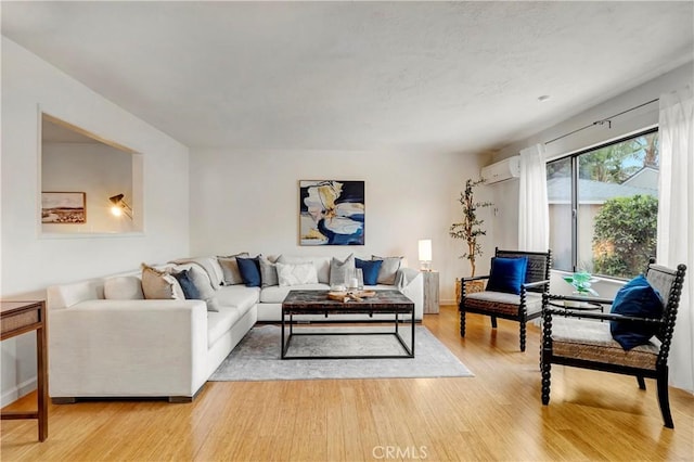 living room with a wall unit AC and light hardwood / wood-style floors