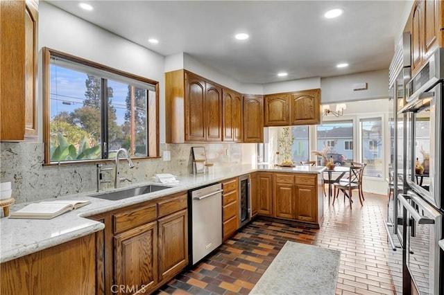 kitchen featuring dishwasher, an inviting chandelier, tasteful backsplash, sink, and light stone counters