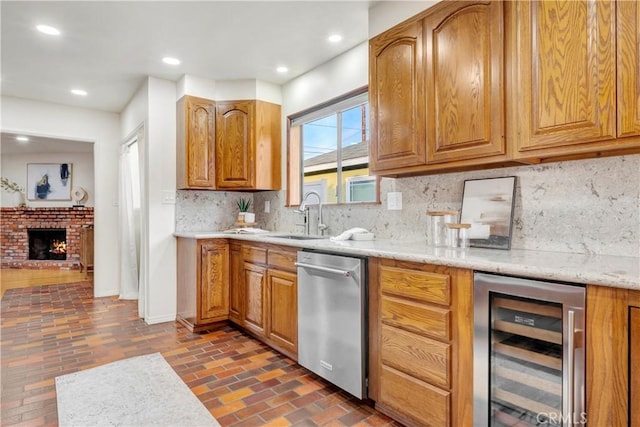 kitchen with beverage cooler, a fireplace, tasteful backsplash, sink, and stainless steel dishwasher