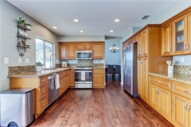 kitchen with stainless steel appliances, tasteful backsplash, dark hardwood / wood-style flooring, light stone countertops, and sink