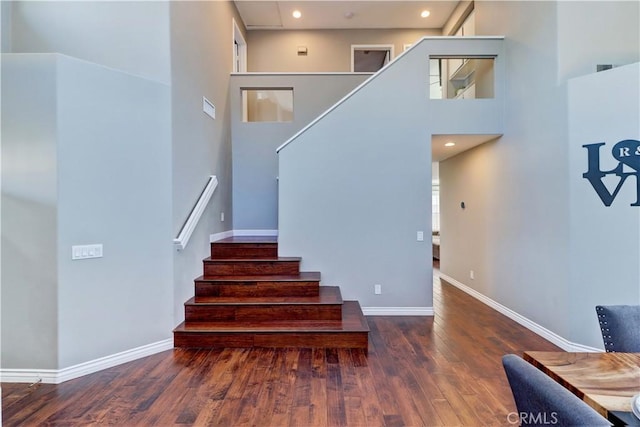 stairs featuring wood-type flooring and a towering ceiling