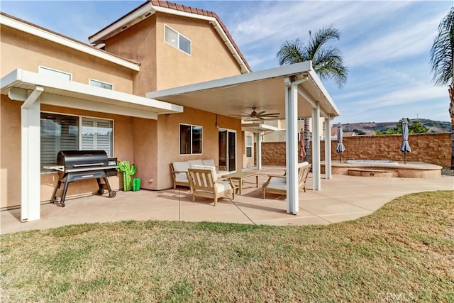 rear view of house with ceiling fan, a patio area, and a lawn