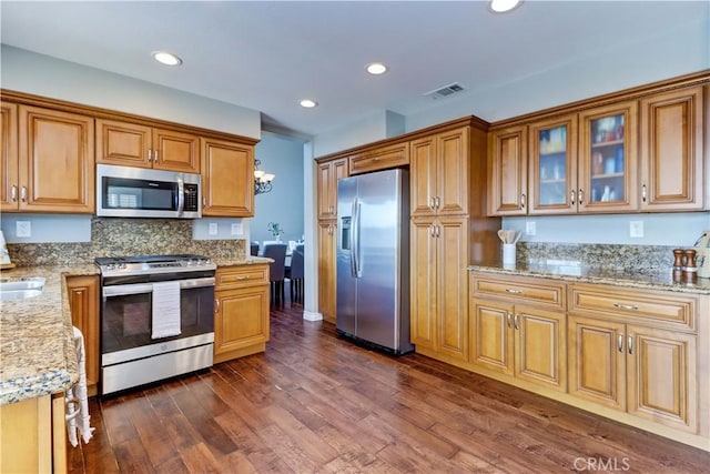 kitchen featuring stainless steel appliances, decorative backsplash, dark hardwood / wood-style floors, and light stone counters