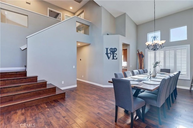 dining room with dark wood-type flooring, a towering ceiling, and a notable chandelier