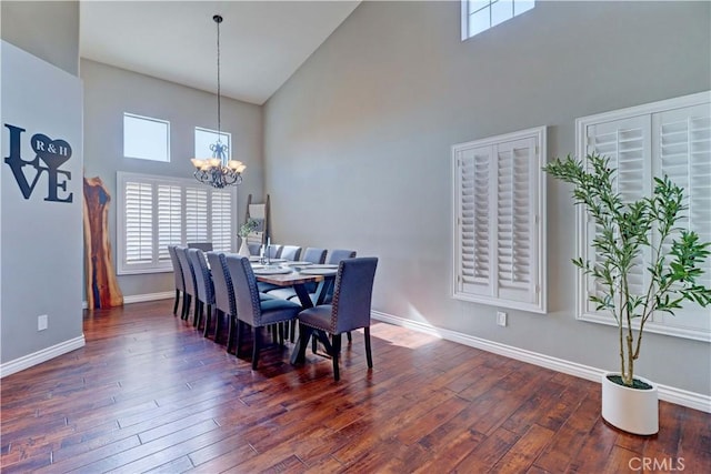 dining space featuring a high ceiling, dark hardwood / wood-style flooring, and a notable chandelier