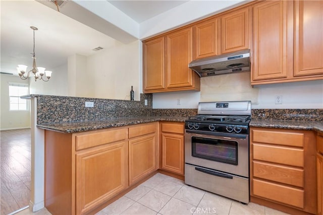 kitchen with a notable chandelier, gas stove, pendant lighting, light tile patterned floors, and dark stone counters