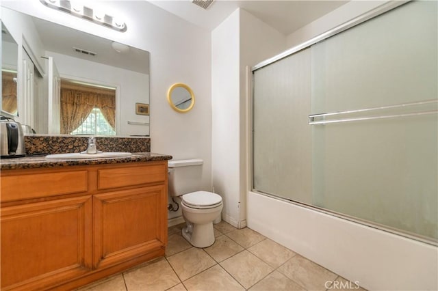 full bathroom featuring bath / shower combo with glass door, toilet, vanity, and tile patterned flooring