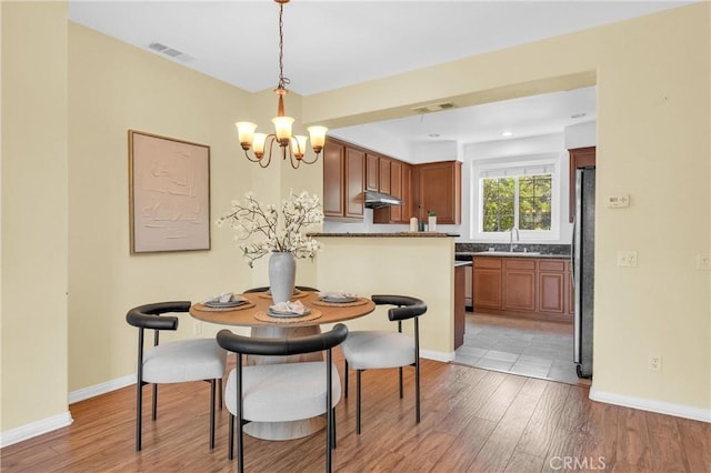 13637 Foster Ave Unit 5, Baldwin Park, CA 91706 - dining area featuring a chandelier, light wood-style floors, and baseboards