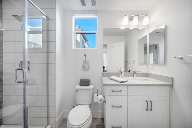 bathroom with toilet, vanity, and a shower with shower door