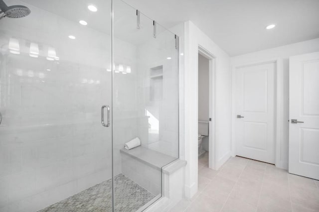 bathroom featuring a shower with shower door, tile patterned floors, and toilet