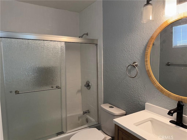 full bathroom featuring toilet, vanity, and shower / bath combination with glass door