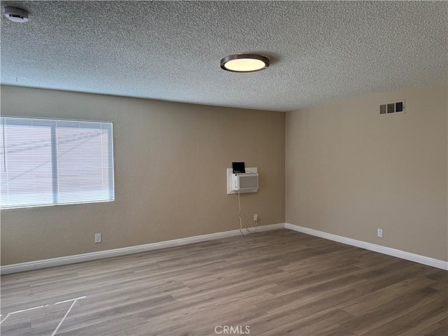 unfurnished room featuring wood-type flooring and a textured ceiling