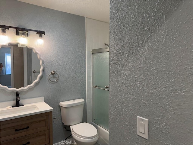 full bathroom with bath / shower combo with glass door, toilet, and vanity