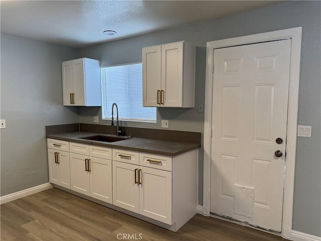 kitchen featuring white cabinetry, hardwood / wood-style flooring, and sink