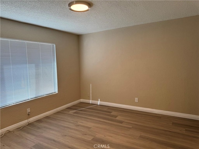 spare room featuring a textured ceiling and hardwood / wood-style floors