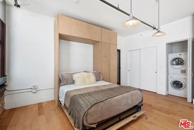 bedroom with stacked washer and clothes dryer and light hardwood / wood-style flooring