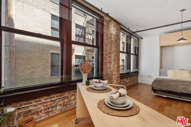 bedroom featuring brick wall, multiple windows, and hardwood / wood-style flooring