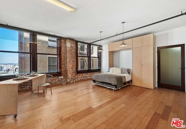 unfurnished bedroom with light hardwood / wood-style floors and brick wall