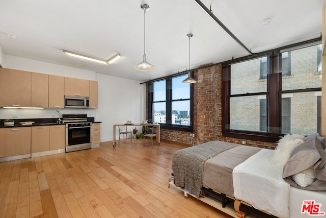 bedroom featuring brick wall and light hardwood / wood-style floors