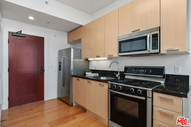 kitchen featuring light brown cabinets, sink, dark stone countertops, and stainless steel appliances