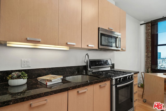 kitchen featuring sink, light brown cabinets, appliances with stainless steel finishes, and dark stone counters