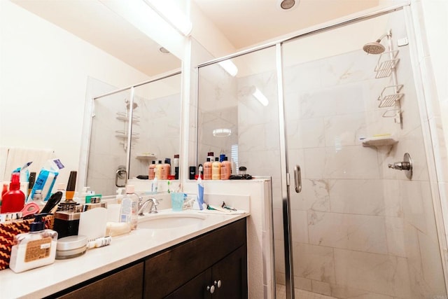 bathroom featuring a shower with shower door and vanity