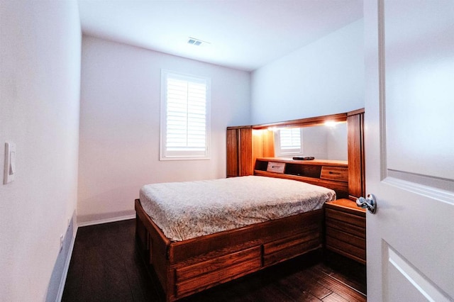 bedroom with dark hardwood / wood-style flooring and multiple windows