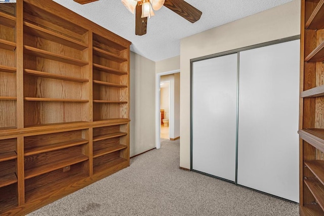 unfurnished bedroom with ceiling fan, a closet, light carpet, and a textured ceiling